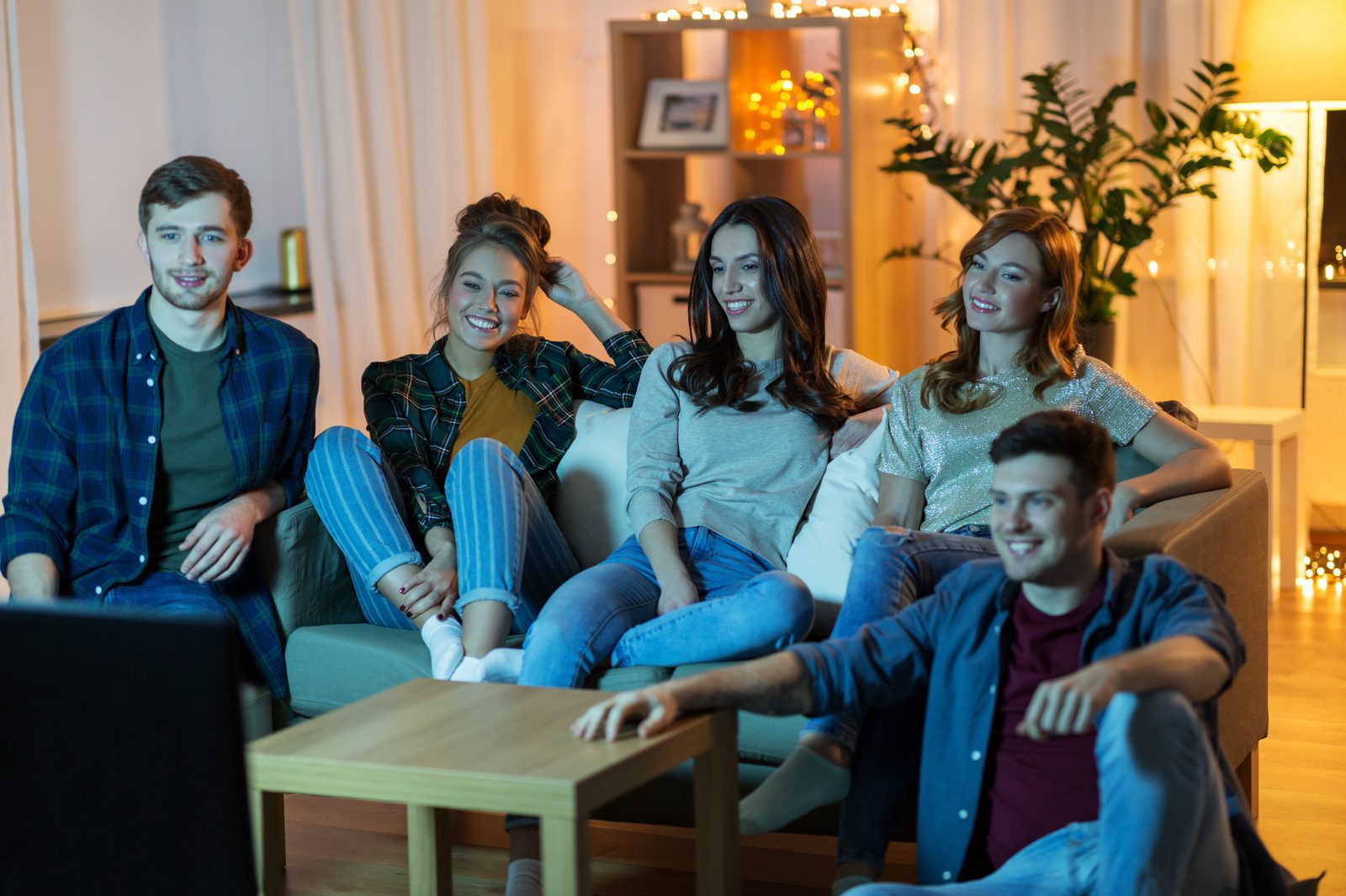 Friends relaxed on a sofa in the evening, watching streaming TV together